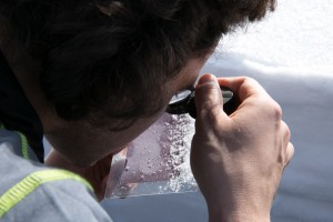 Josh examines the snow crystals to determine their shape.
