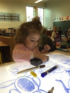 little girl drawing with markers